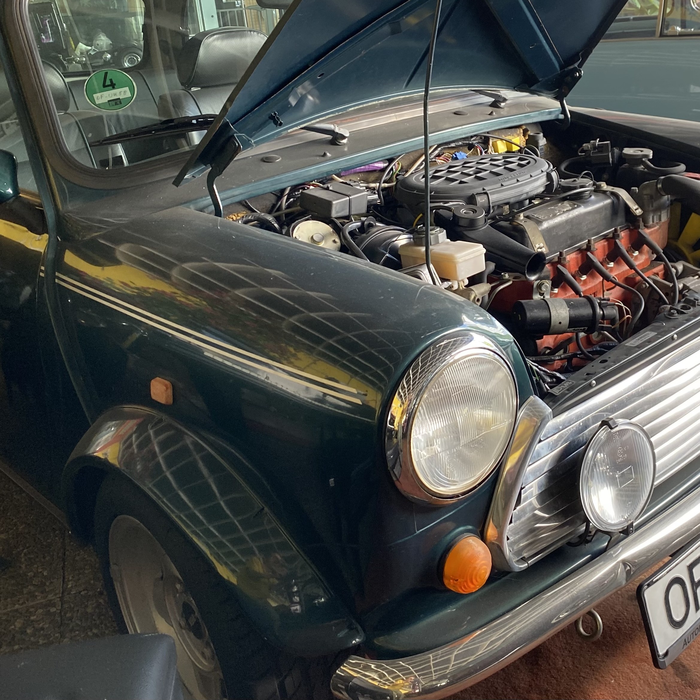 A close-up view of a classic Mini car with its hood open, showcasing the engine and interior details.