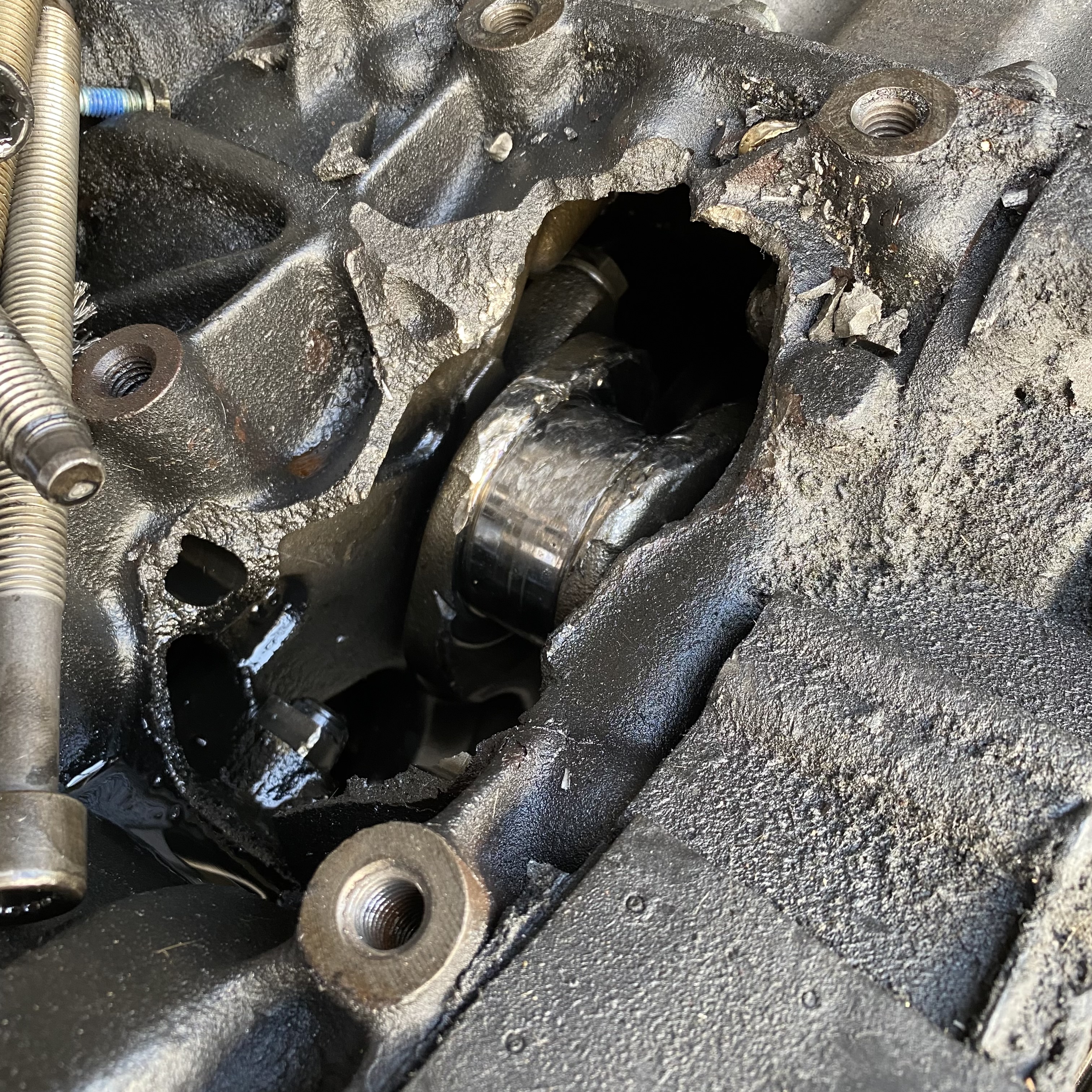 Close-up view of a damaged engine component showing a cracked and corroded surface with visible oil residue.