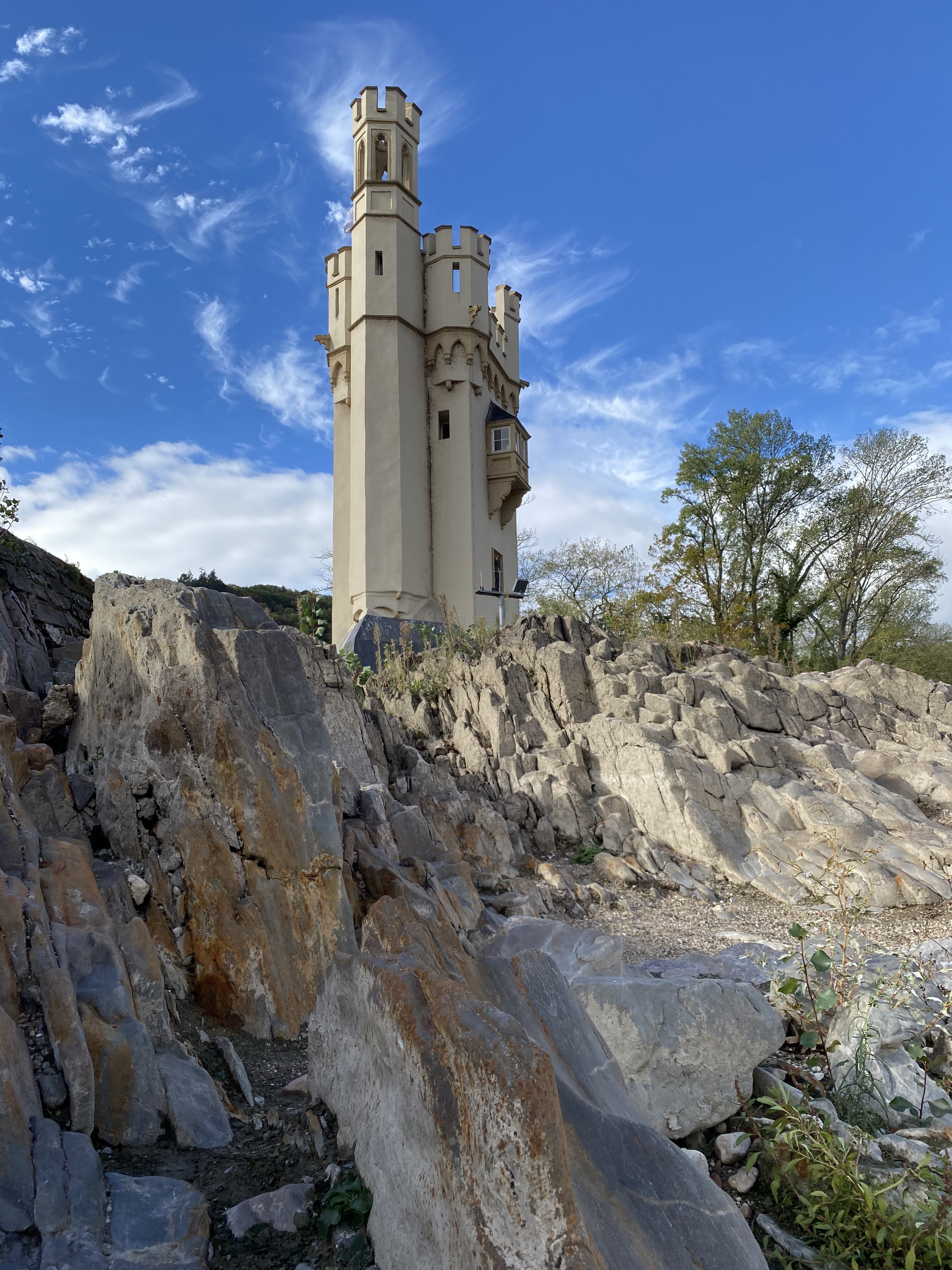 A tall, castle-like structure with turrets, surrounded by rocky terrain and clear blue skies.